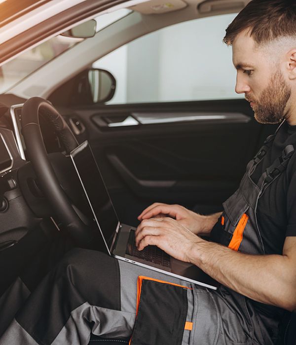 Mechatroniker mit Laptop im Fahrzeug